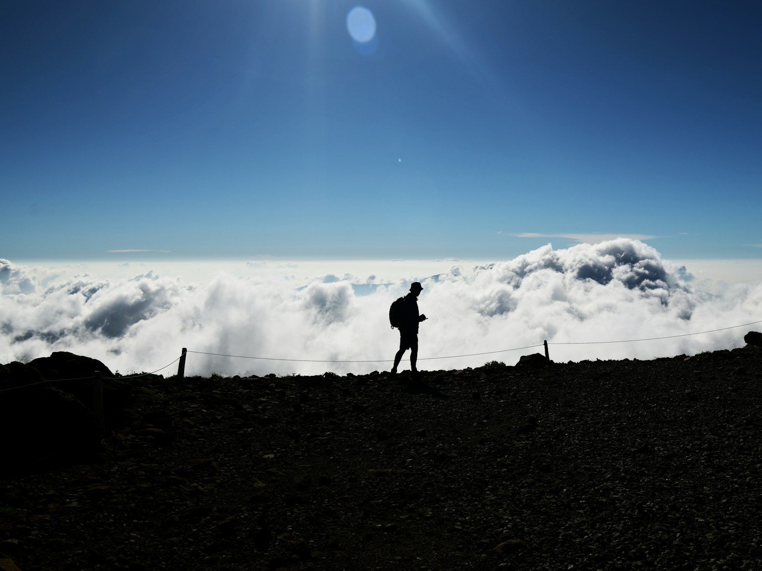 Silhouette di una persona che cammina sopra le nuvole con un cielo blu chiaro