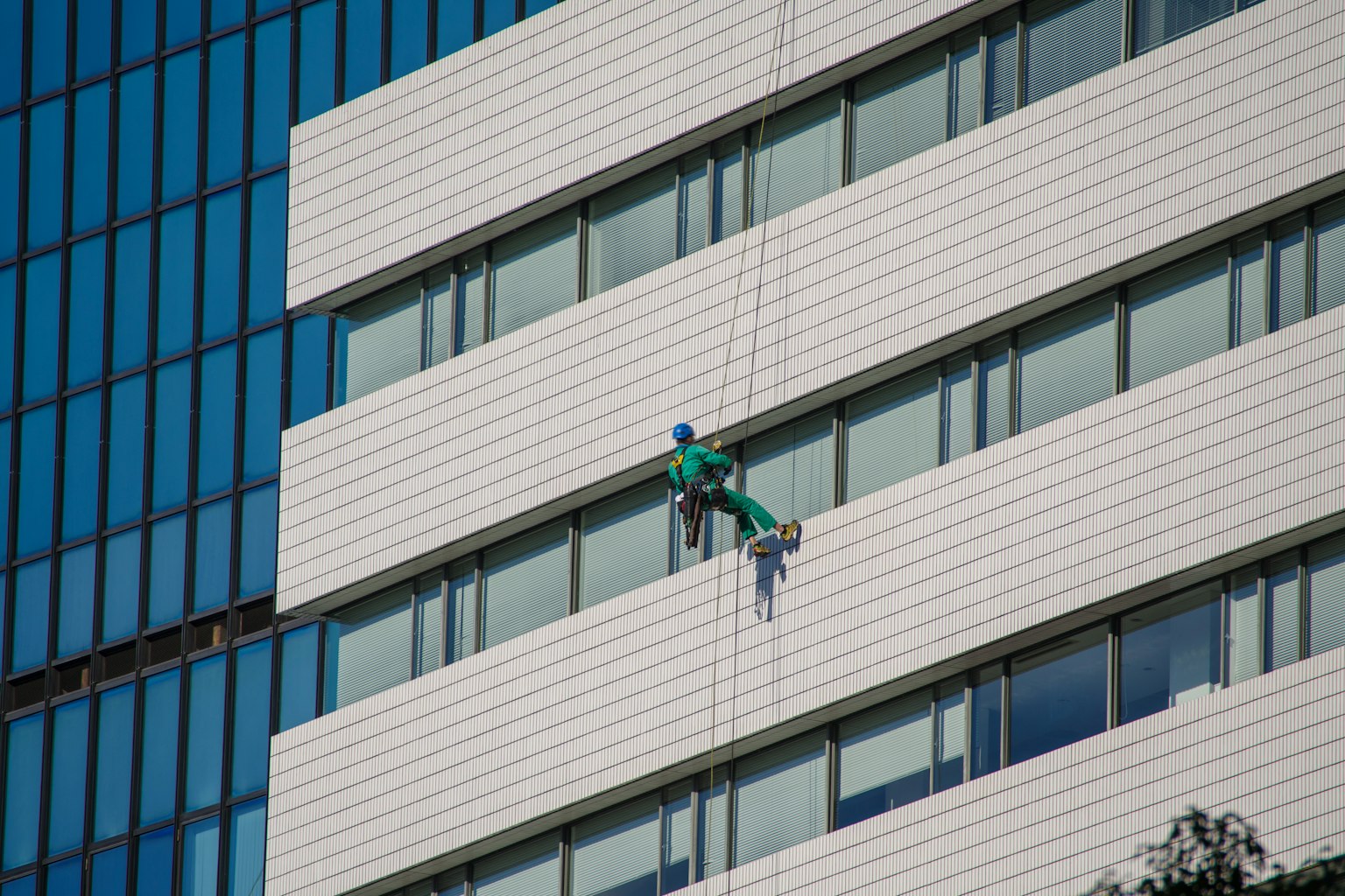 Travailleur en uniforme vert nettoyant l'extérieur d'un bâtiment