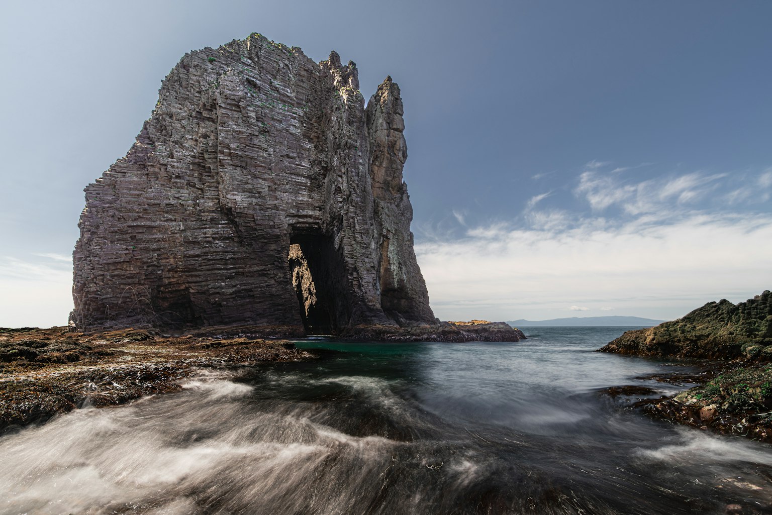 Grande formation rocheuse entourée d'eau avec des vagues