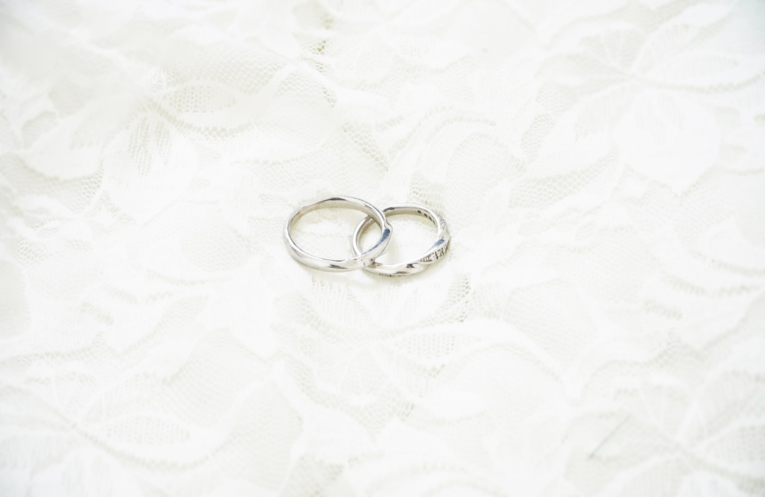 Two silver wedding rings resting on a white fabric surface