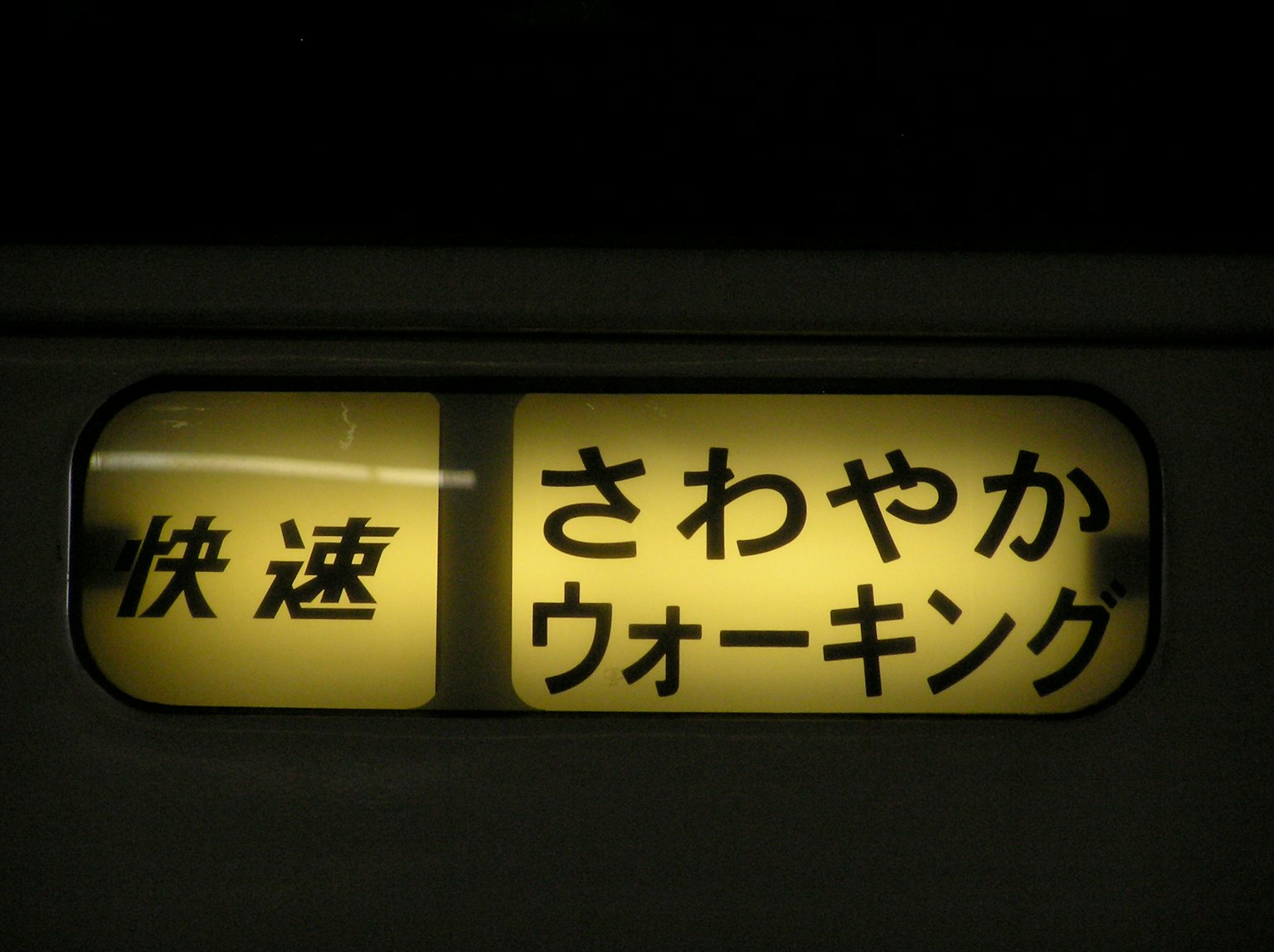 Yellow sign featuring Japanese text reading Rapid and Refreshing Walking