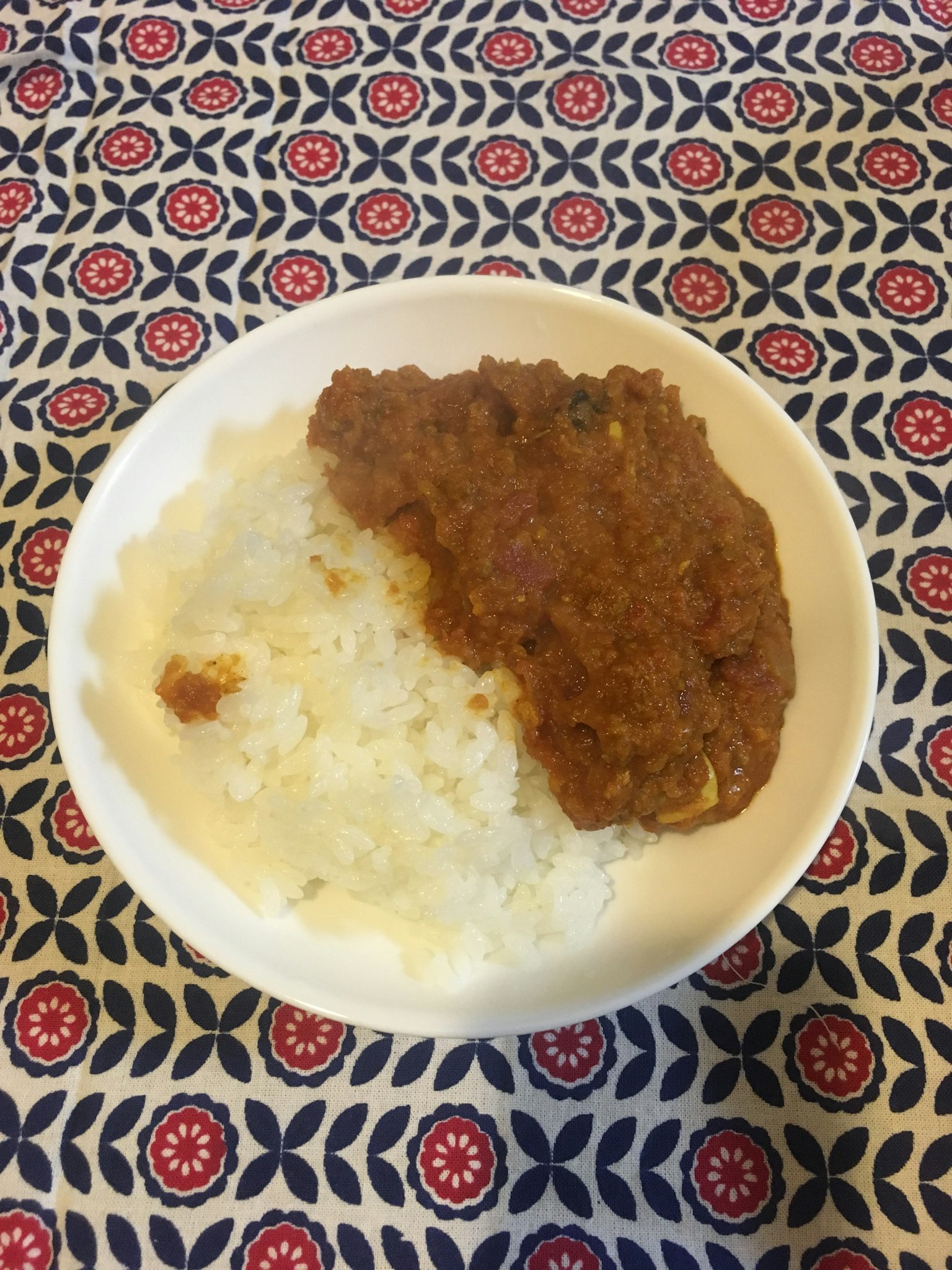 一盤米飯上放著咖哩，背景為多彩桌布