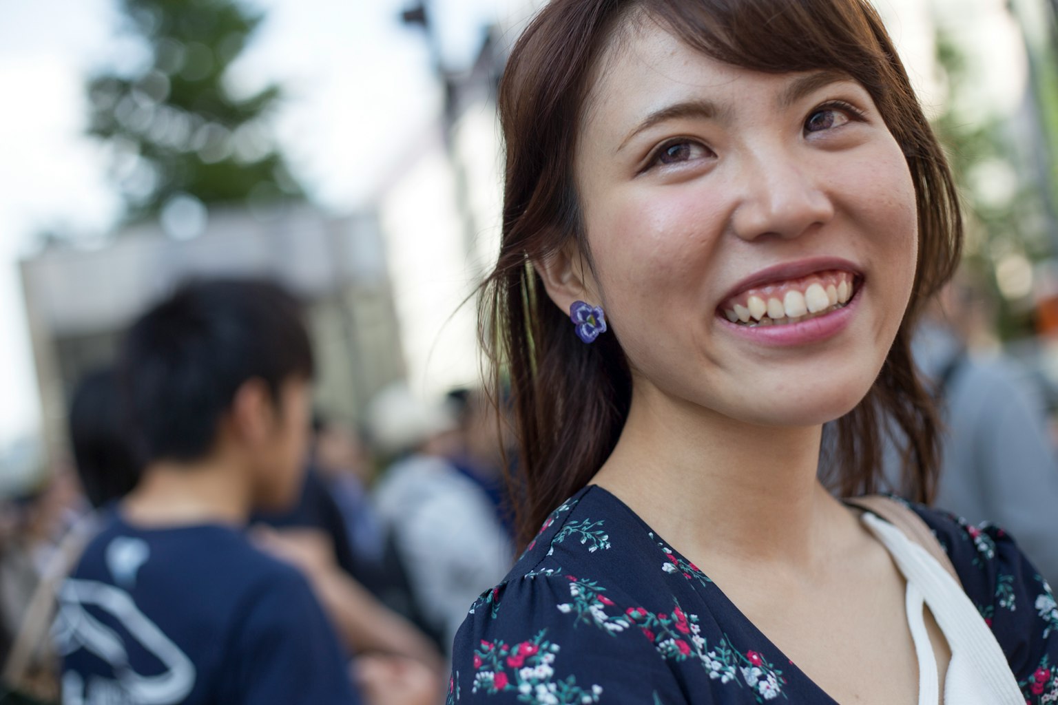 Donna sorridente che indossa un vestito floreale con persone sullo sfondo