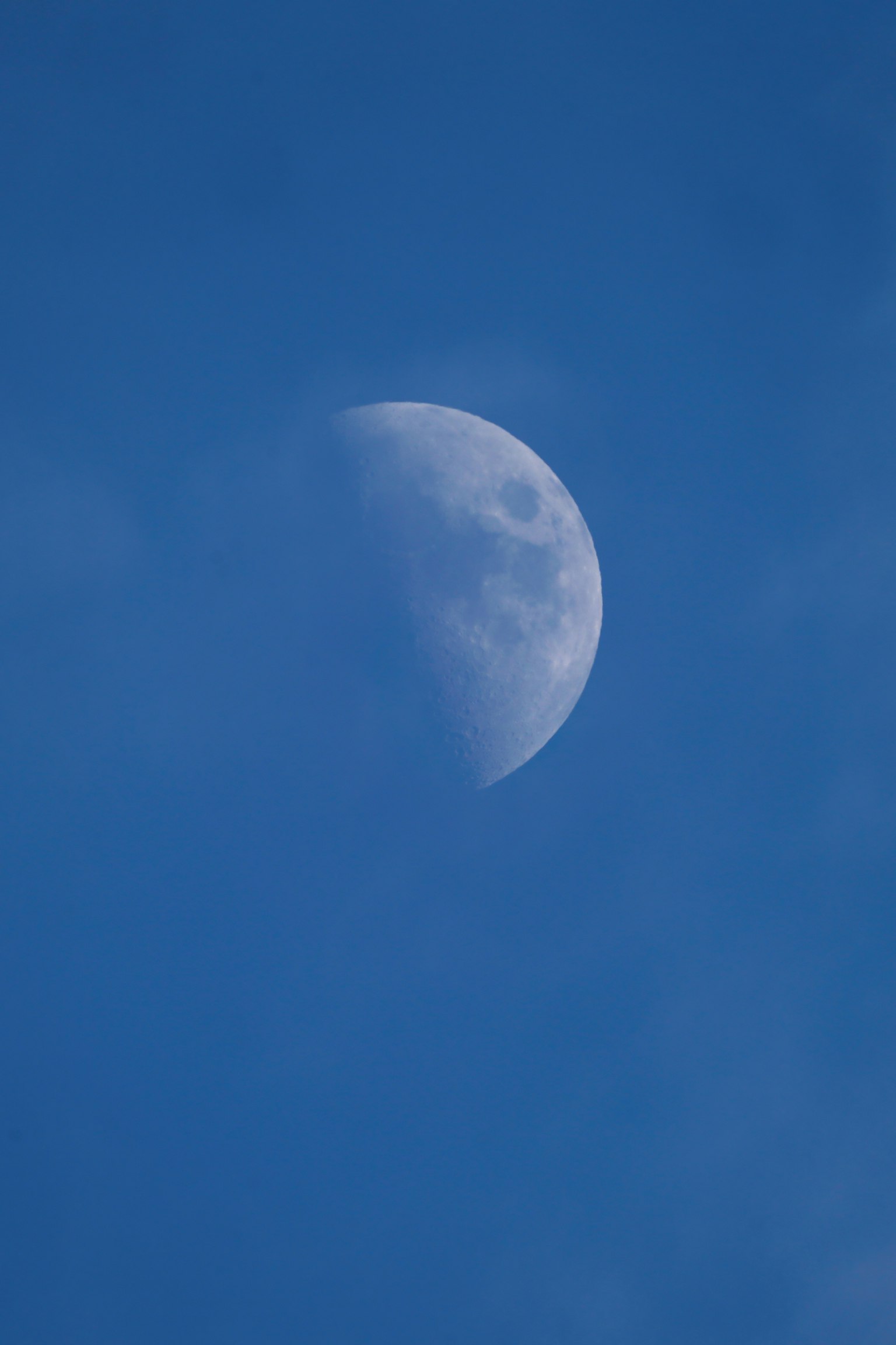 A half moon visible in the blue sky