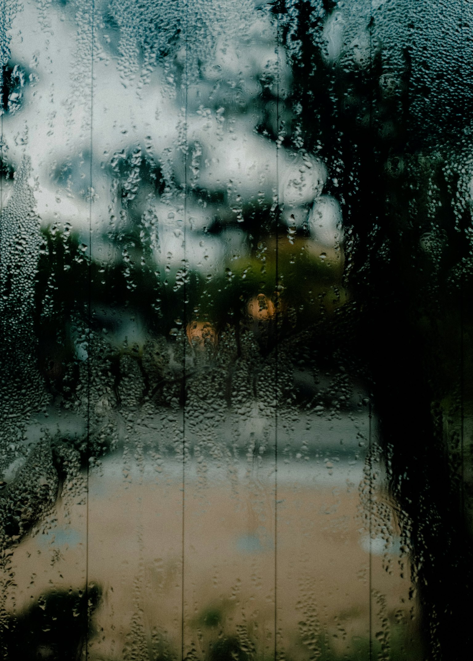 Foggy glass window showing blurred landscape with clouds