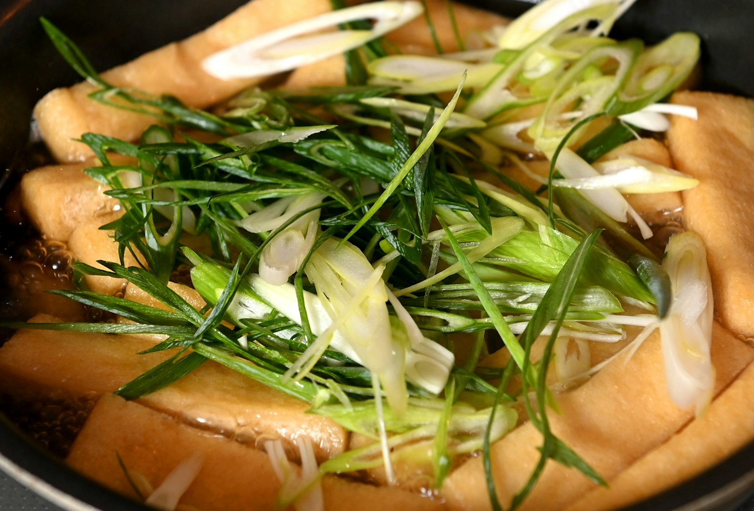 Gericht mit Tofu und geschnittenen Frühlingszwiebeln in einem Topf
