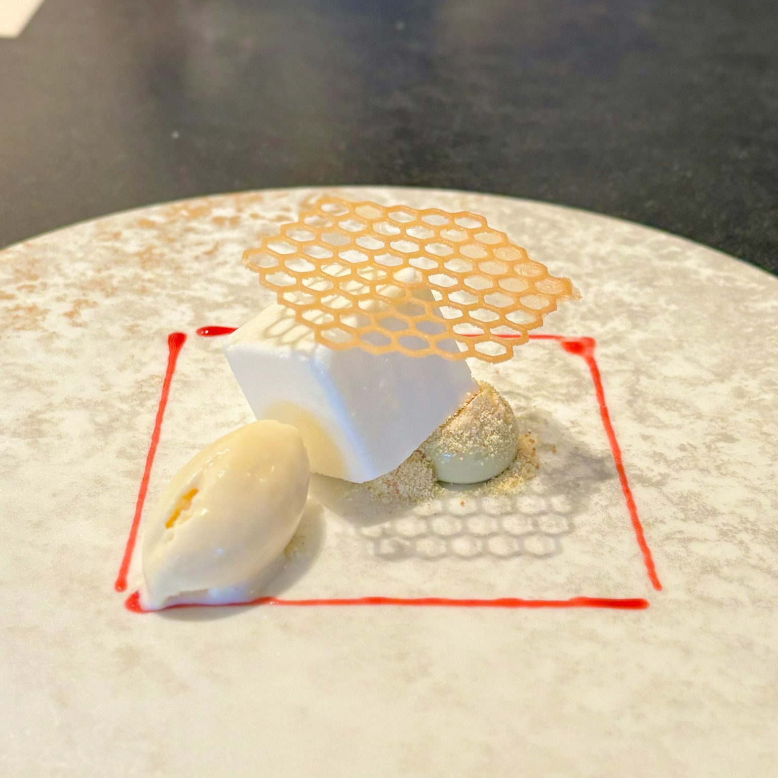 Dessert putih di piring dengan dekorasi berbentuk sarang lebah di atasnya