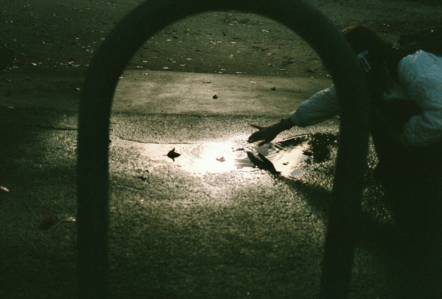 Enfant touchant un reflet sur le sol dans un parc