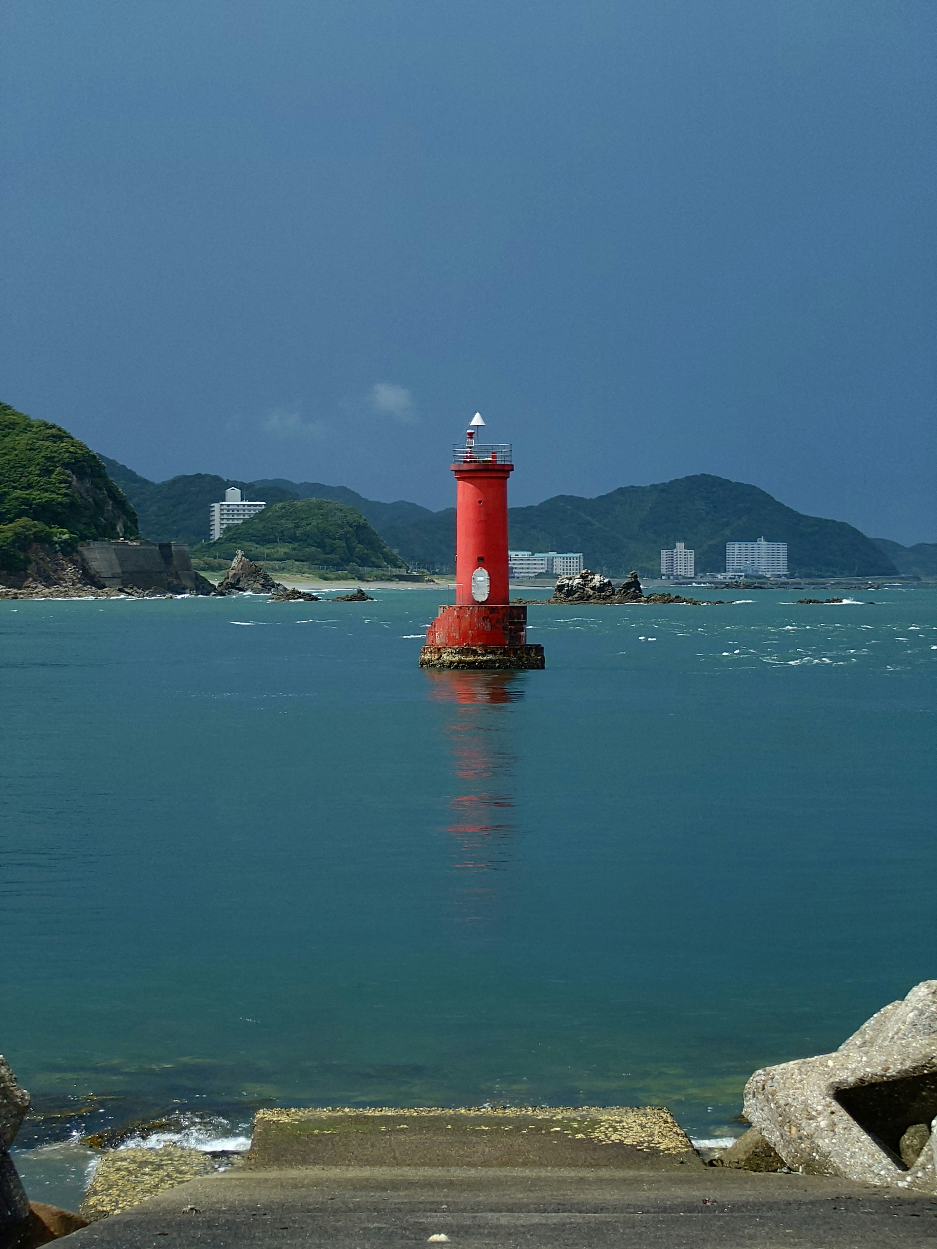 赤い灯標と青い海を見下ろす海辺の景色