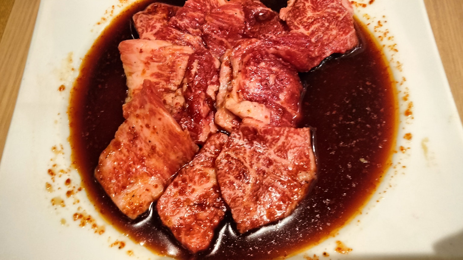 Irisan daging merah yang dimarinasi dalam saus gelap di atas piring