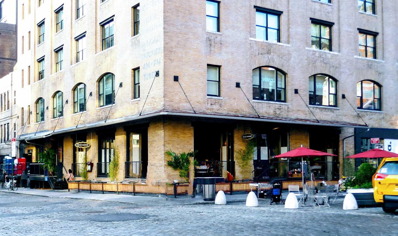 Exterior de un edificio de ladrillo con terraza de café y asientos al aire libre