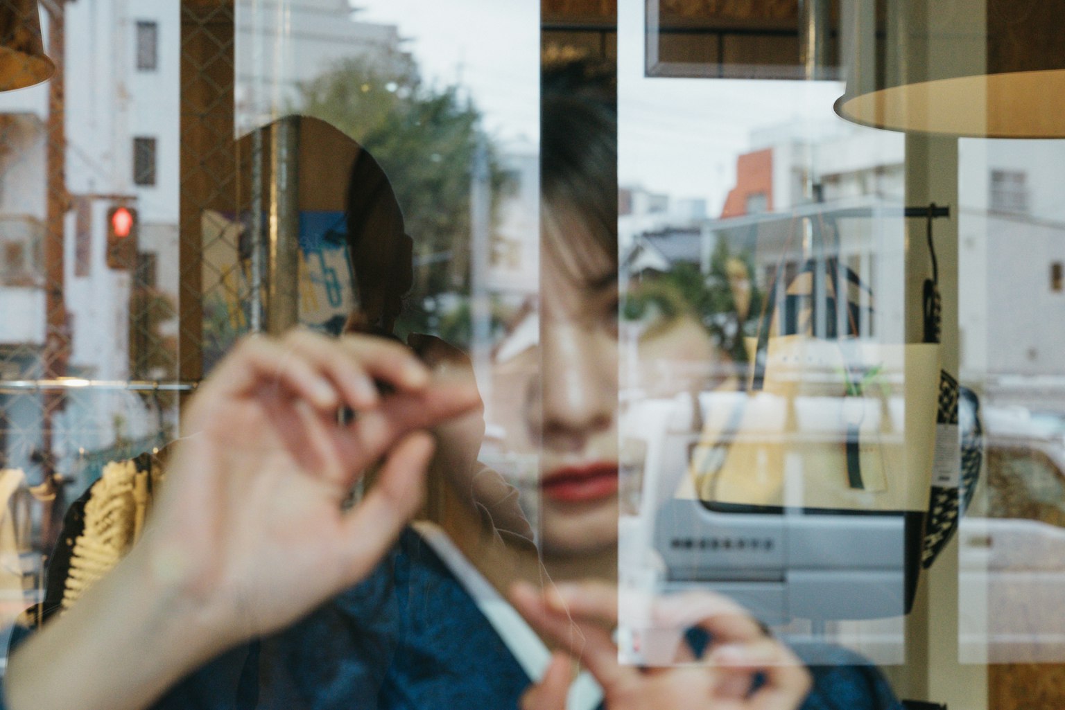 Visage et mouvements de main d'une femme vus à travers une fenêtre reflétant le paysage urbain