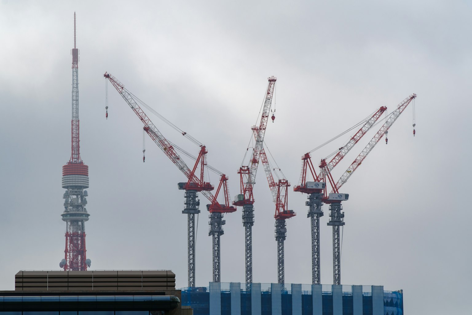 Tokyo Tower and construction cranes in a cloudy sky