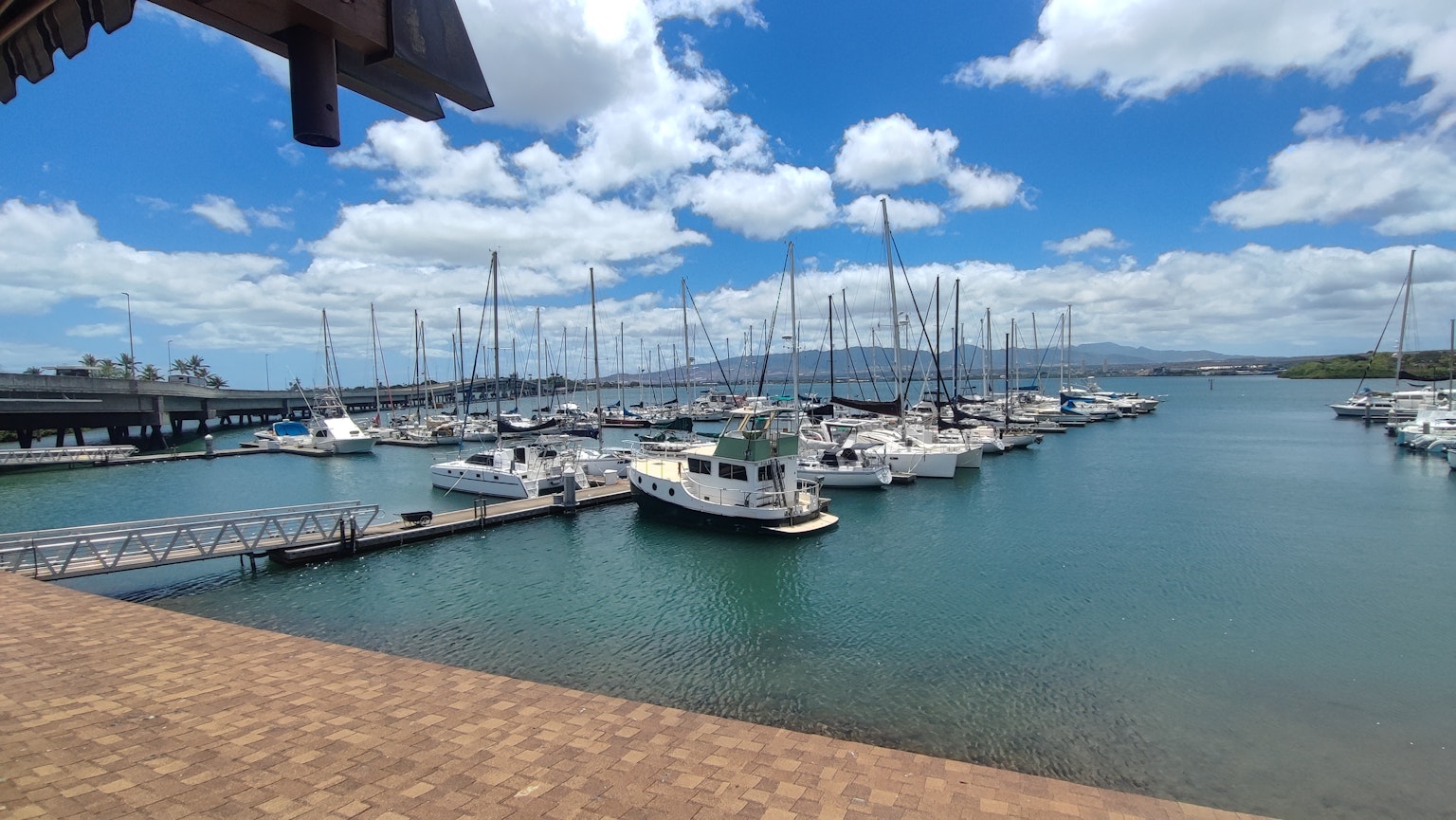 Vue panoramique d'un port de plaisance avec des bateaux et des yachts amarrés sous un ciel bleu et des nuages blancs