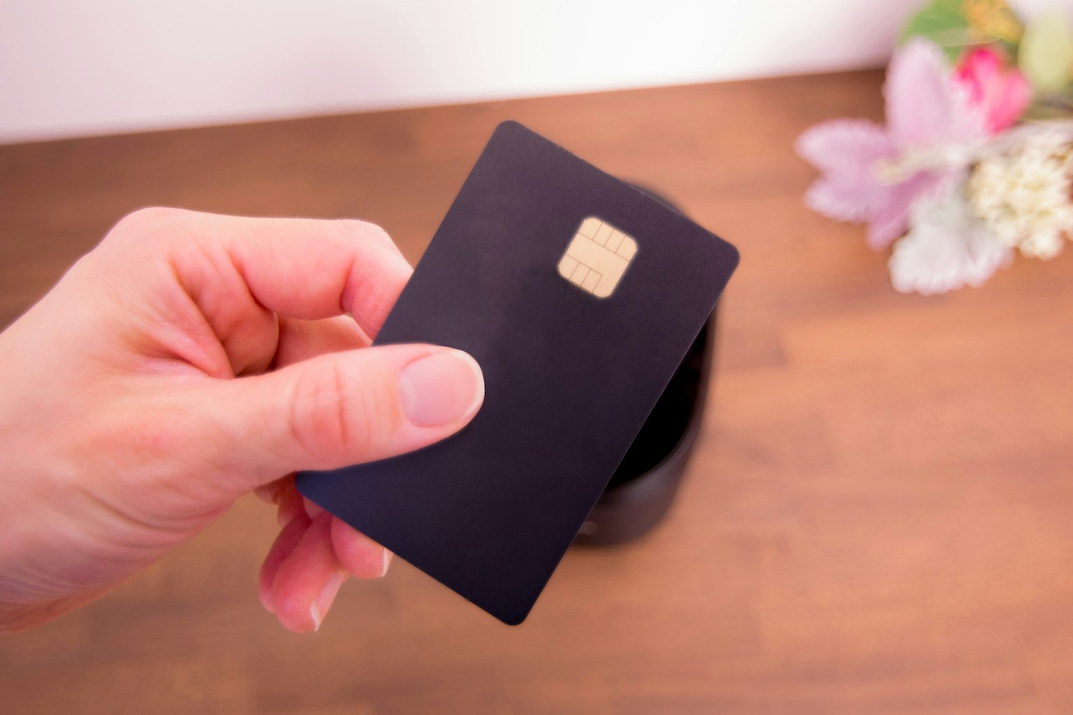 Une main tenant une carte noire avec une puce entourée de fleurs