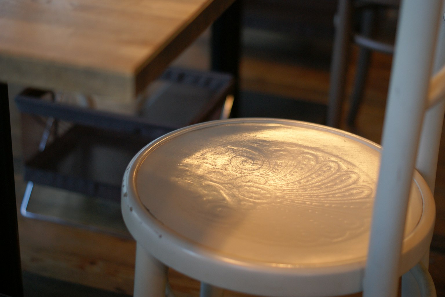 Pattern reflected on the white stool seat with a wooden table in the background