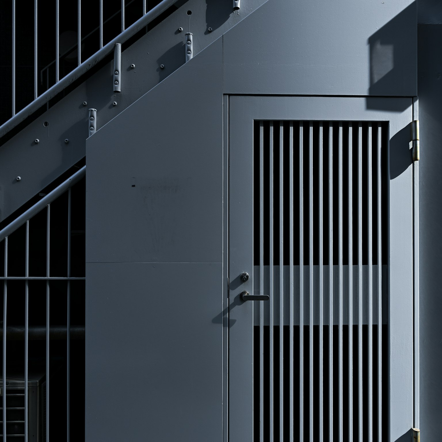 Stahltür in der Nähe einer Treppe mit vertikalen Lamellen und modernem Design