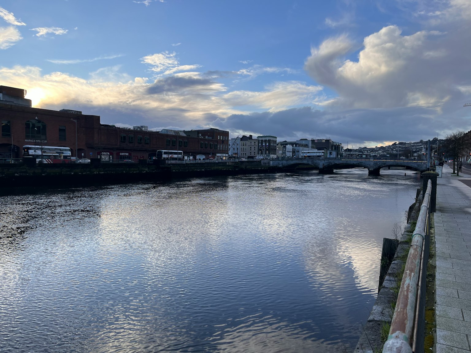 Vista panoramica di un fiume che riflette nuvole e edifici con un ponte