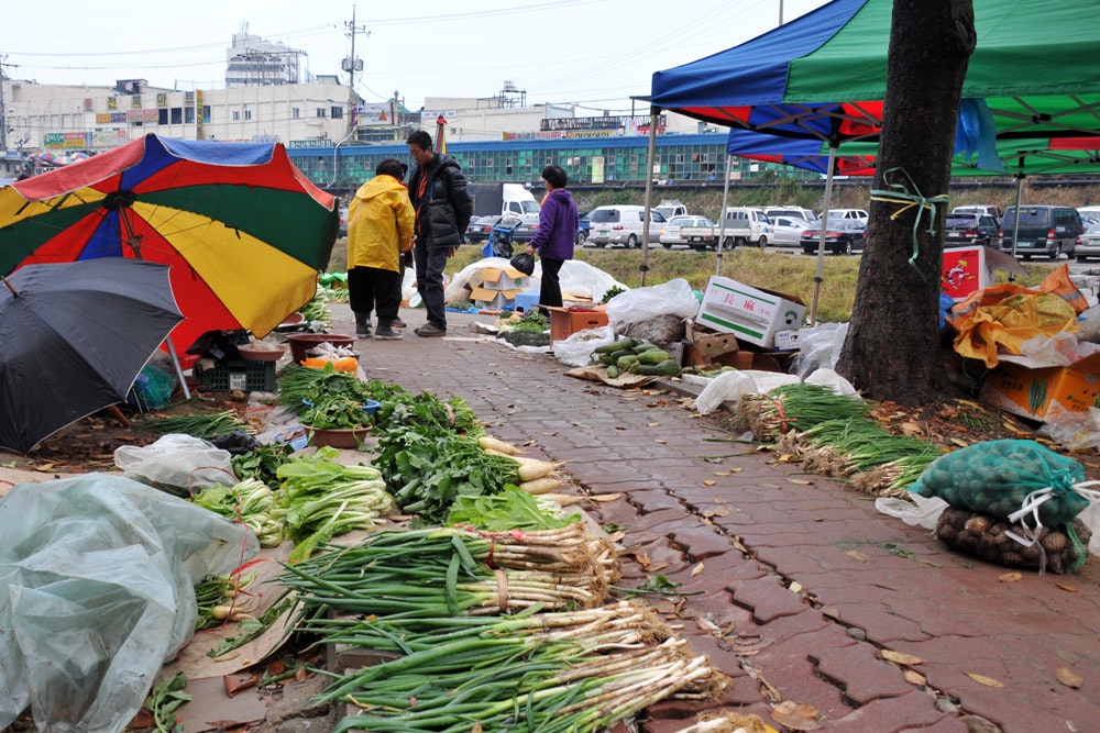 韓国の全羅北道の野外市場で並ぶ野菜とテントのある通り