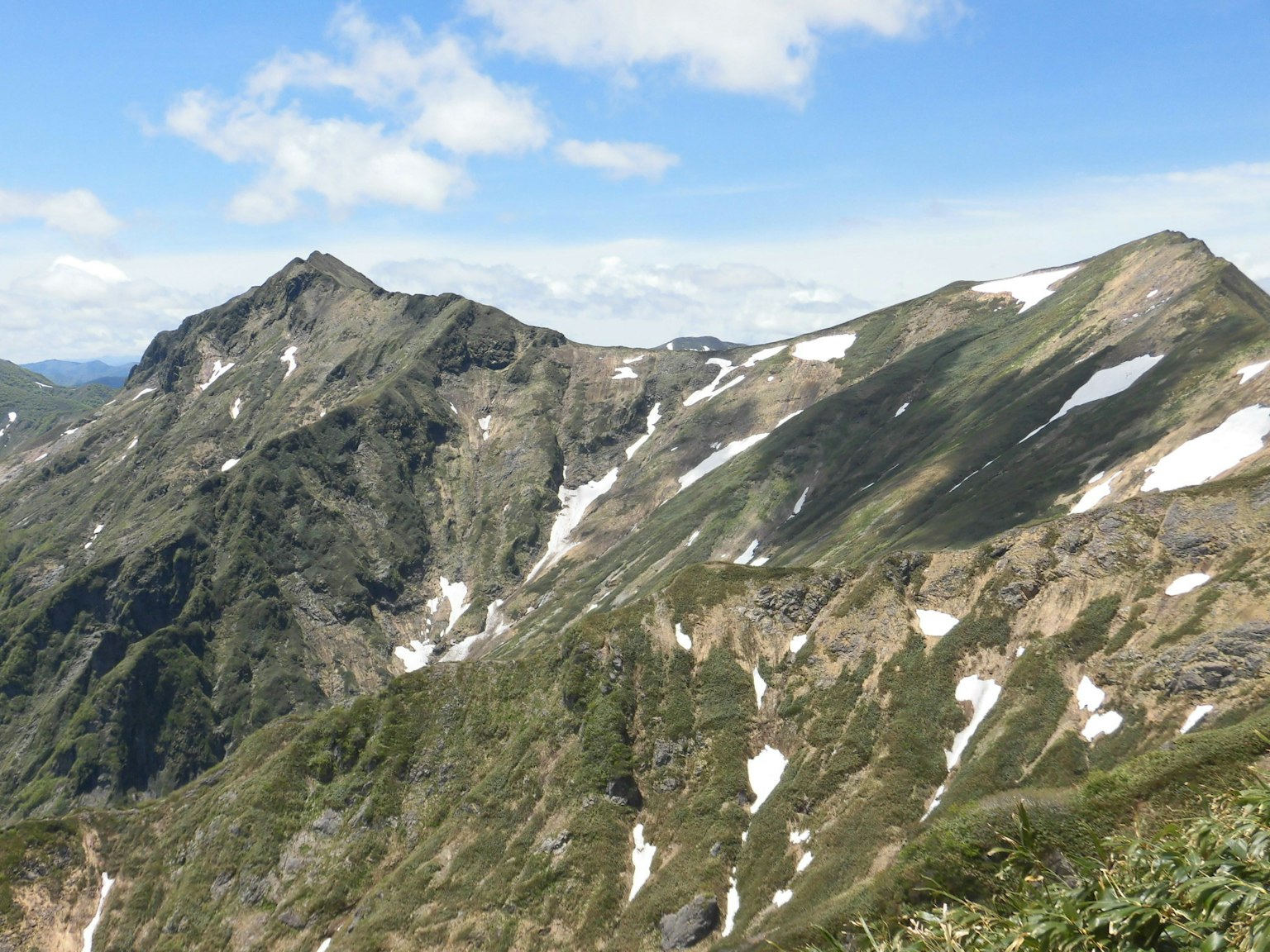 Paisaje montañoso escénico con prados verdes y picos nevados