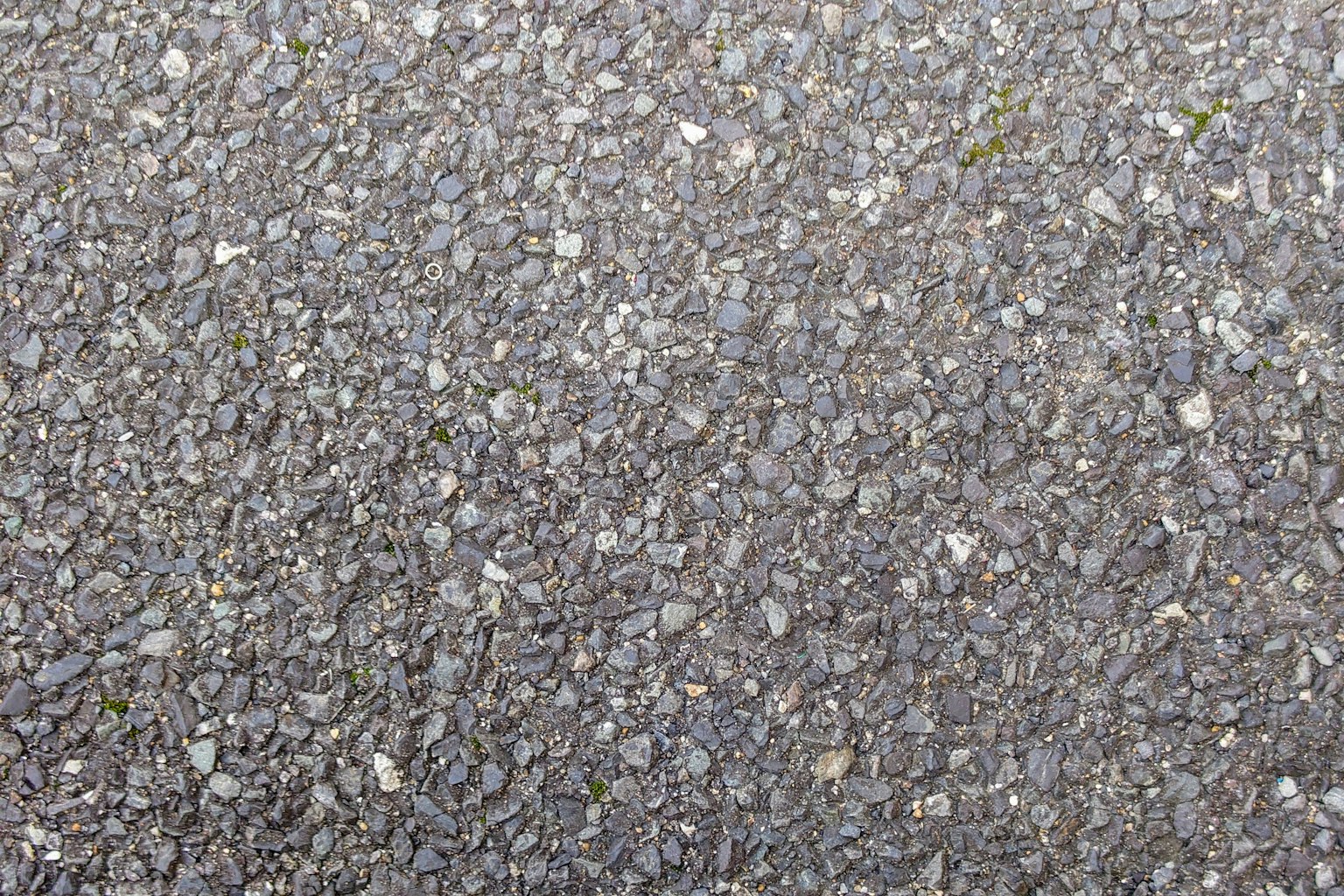 Close-up of asphalt surface showing small stones and gravel texture