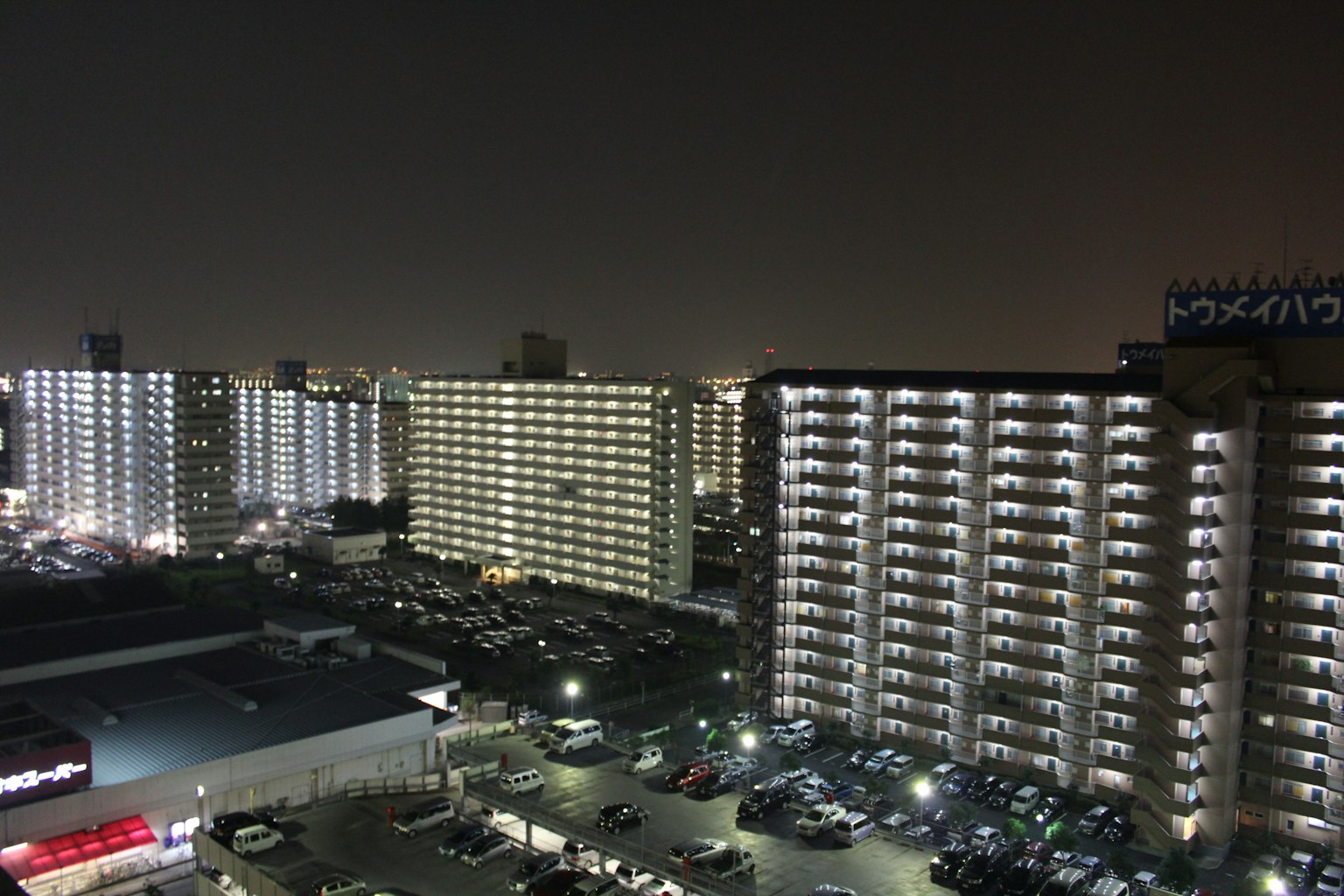 Night cityscape featuring high-rise buildings and illuminated parking lots