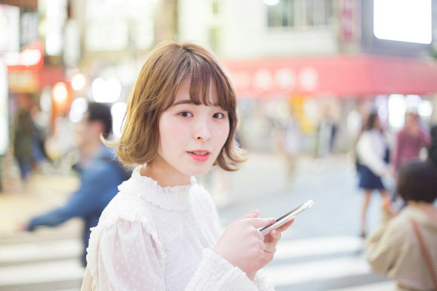 Potret seorang wanita memegang smartphone di persimpangan kota