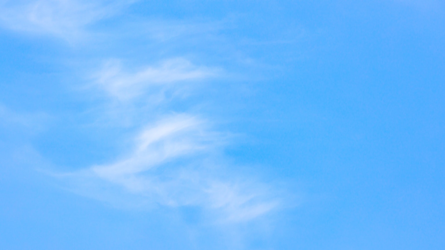 Un paysage simple avec des nuages filandreux dérivant dans un ciel bleu