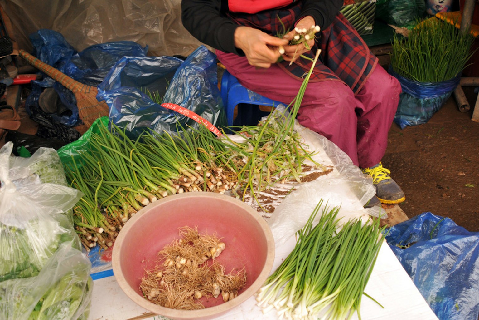 Một người phụ nữ đang chuẩn bị hành lá tại chợ