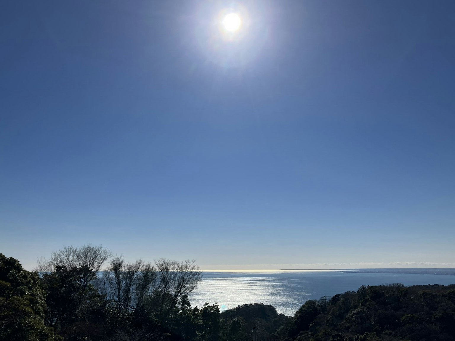 Cielo blu luminoso con un sole splendente sopra le acque oceaniche calme