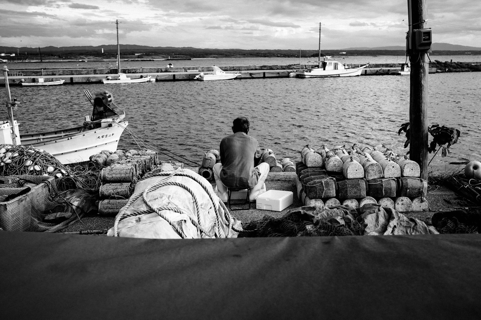 Immagine in bianco e nero di un uomo che lavora sulla spiaggia con barche da pesca
