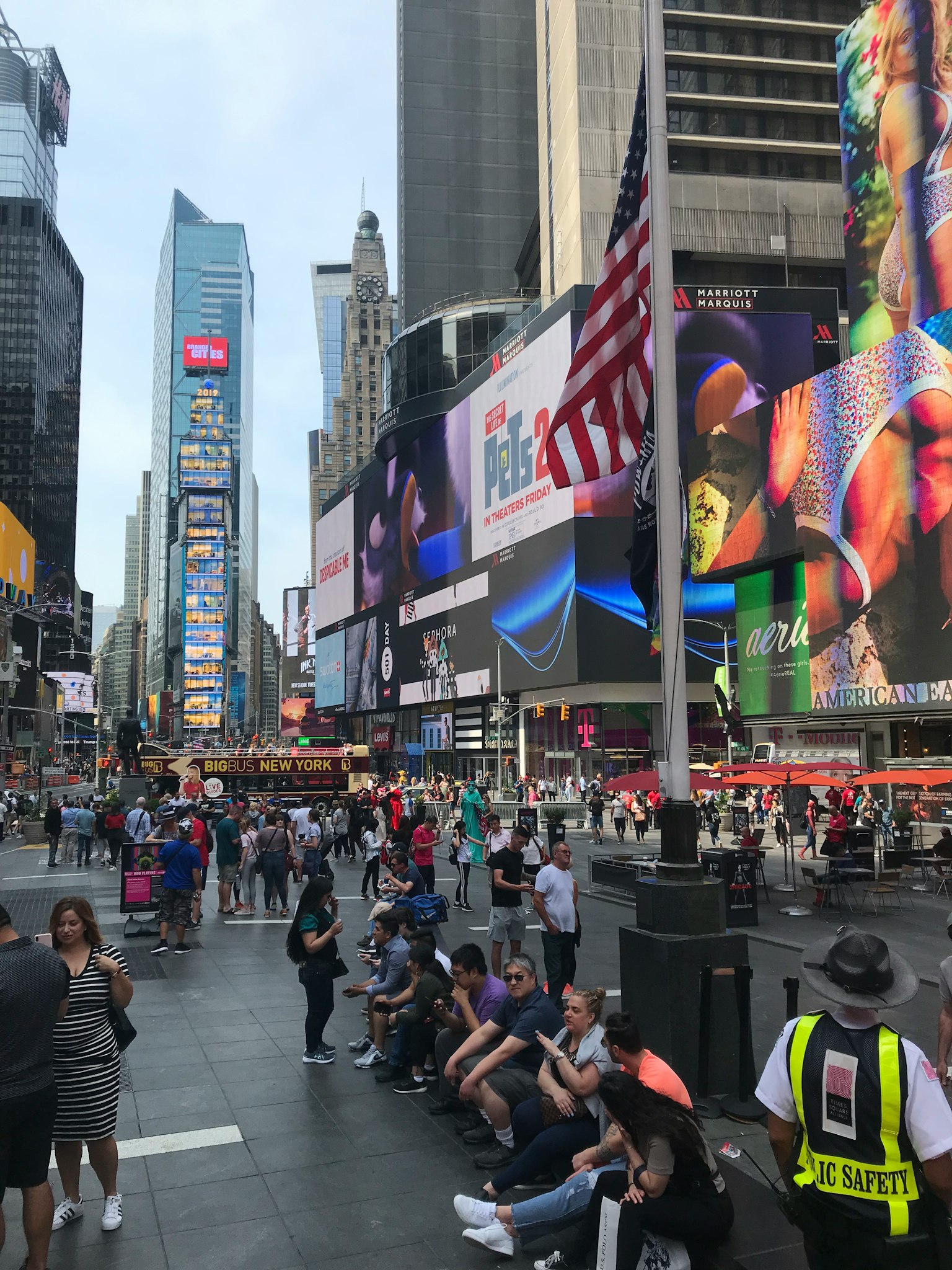 Busy scene in Times Square featuring the American flag and crowds of people