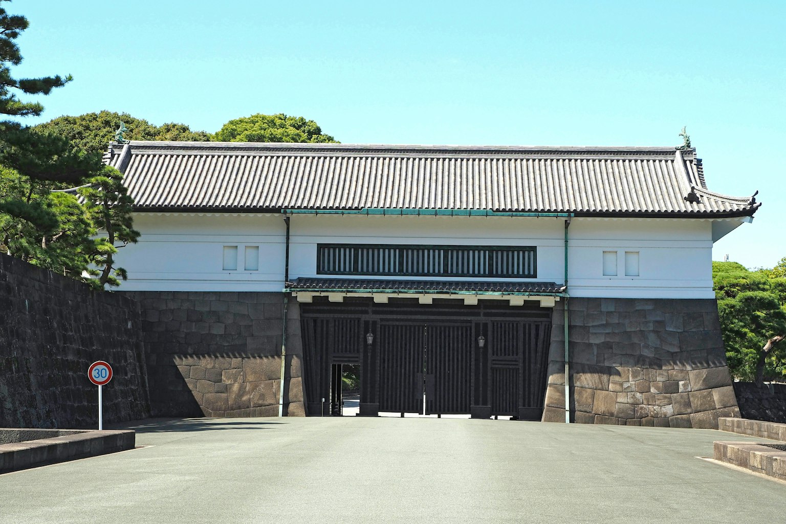 Porta storica a Tokyo con muri bianchi e porte nere sotto un cielo blu chiaro
