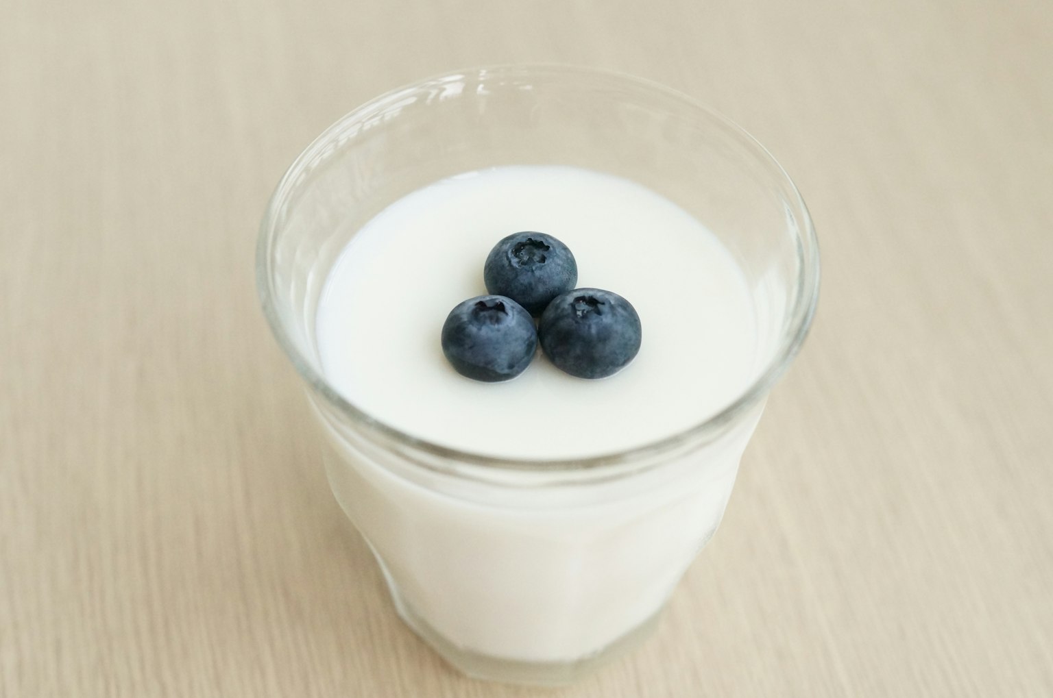 Un vaso de yogur cubierto con tres arándanos