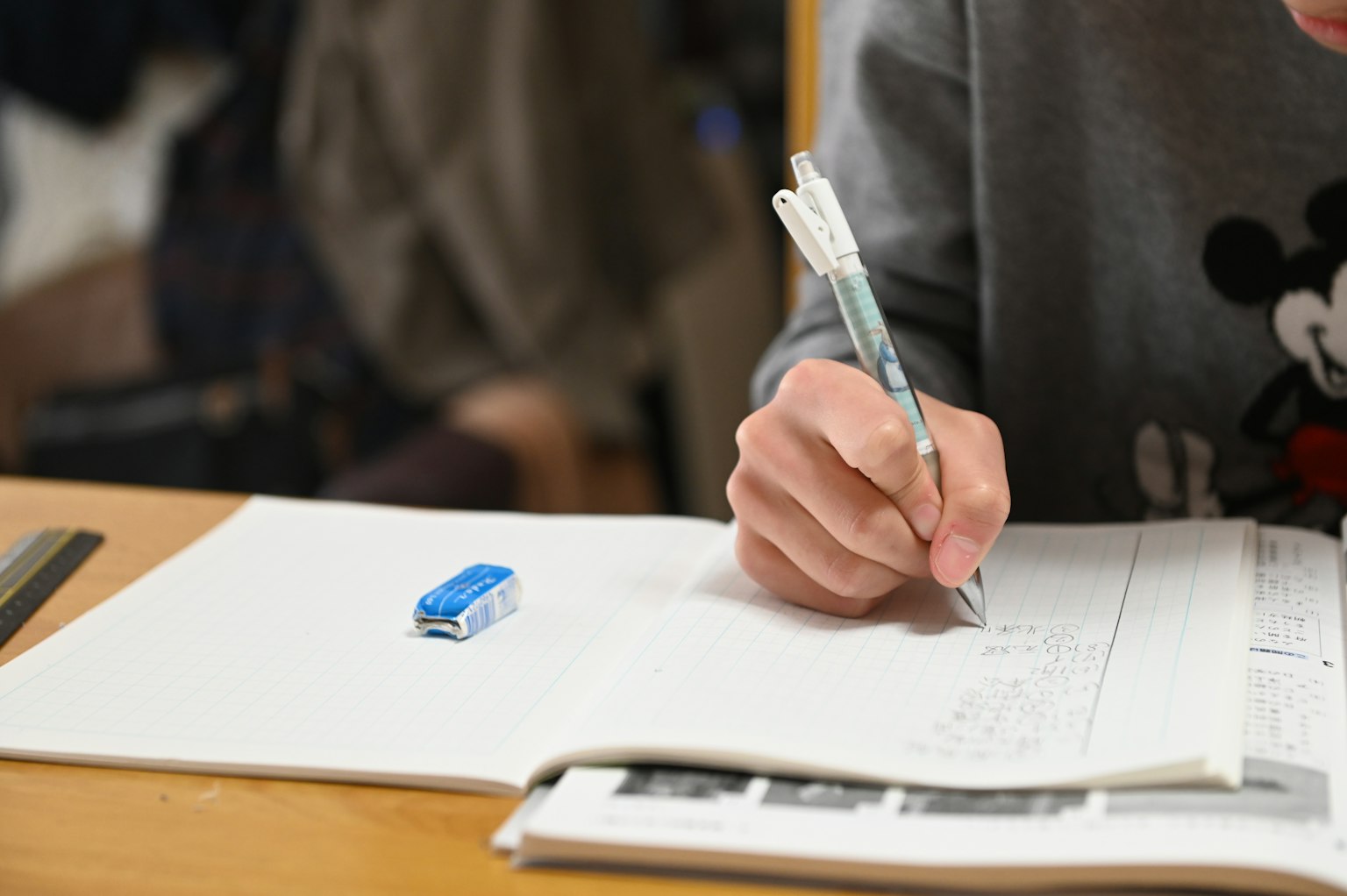 Nahaufnahme einer Hand, die mit einem Stift in ein Notizbuch schreibt