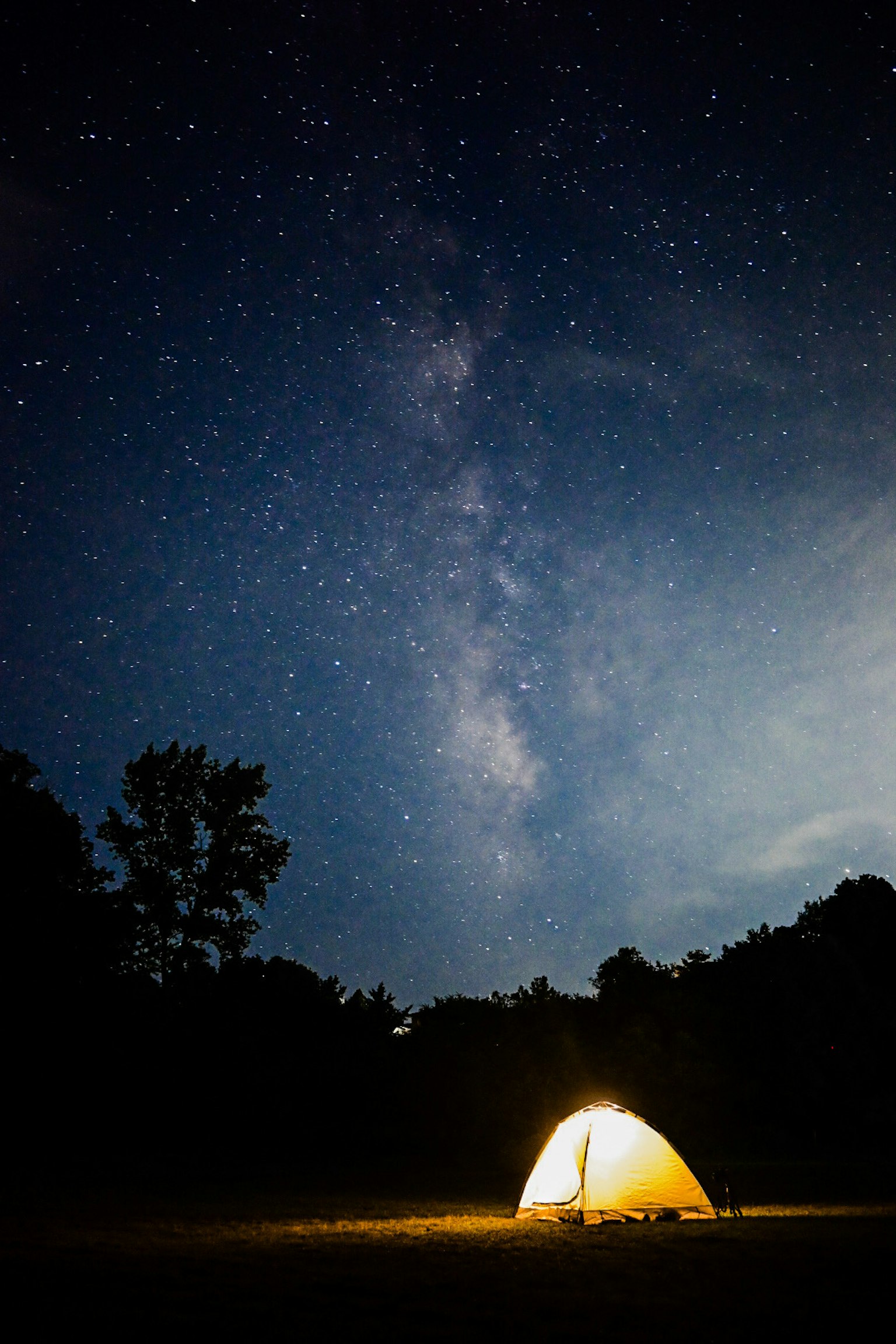 Tenda illuminata sotto un cielo stellato con la Via Lattea