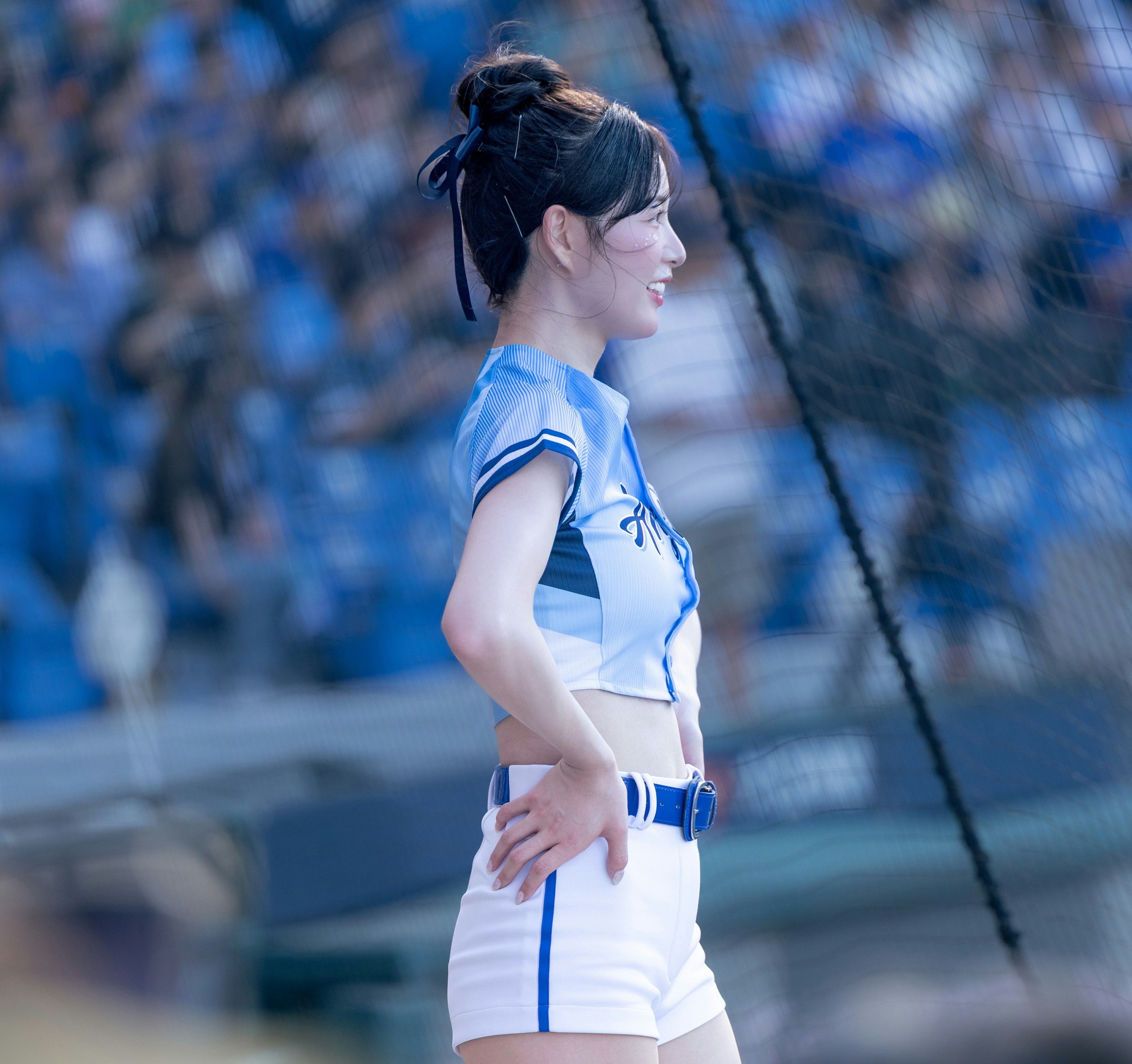 青いスタジアムで走るユニフォーム姿の女性