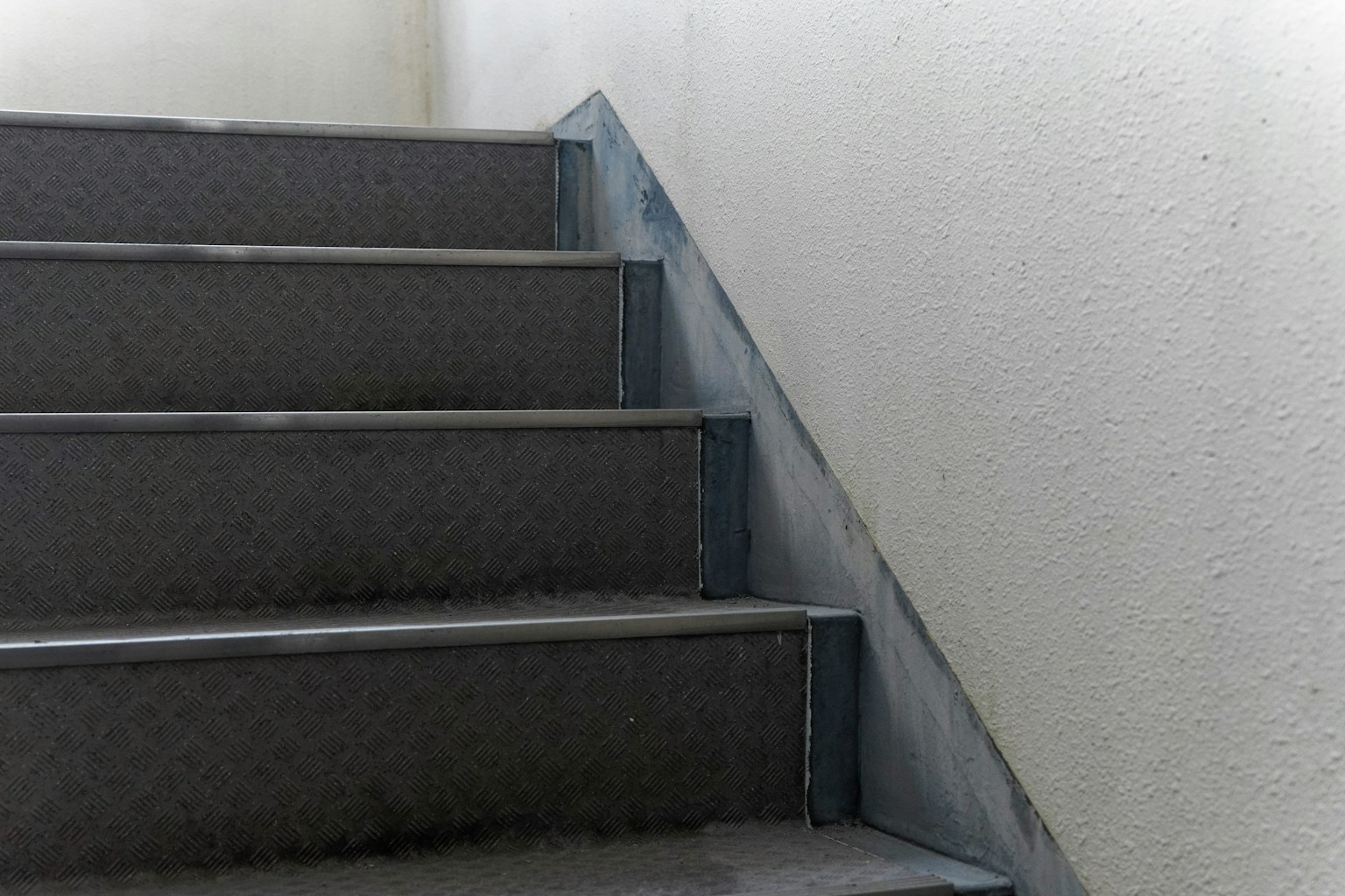 ภาพที่แสดงส่วนหนึ่งของบันไดมีขั้นบันไดสีเทาและราวเหล็ก