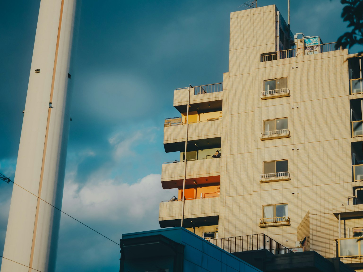 Paysage urbain avec un immeuble de grande hauteur et des balcons colorés sous un ciel bleu