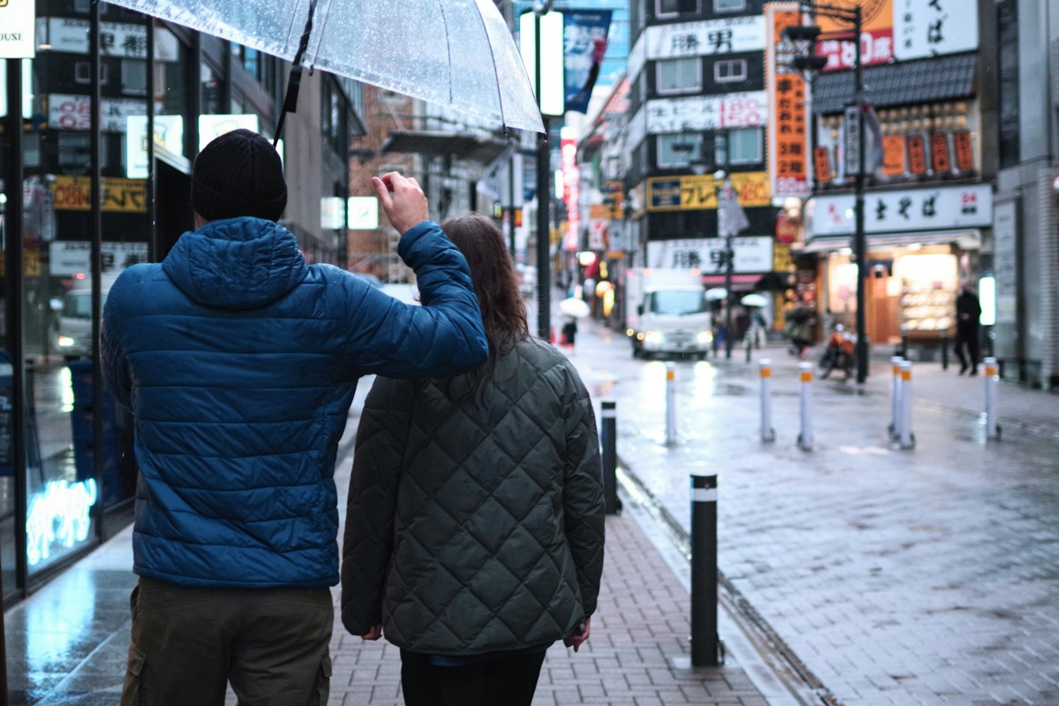 คู่รักเดินในฝนถือร่มอยู่บนถนนในเมือง
