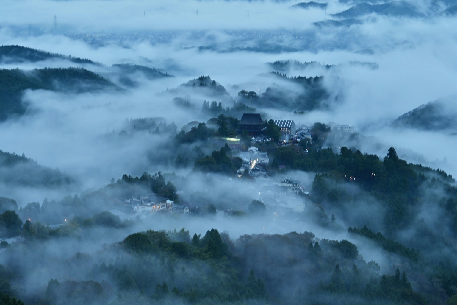 Un pueblo enclavado en las montañas envuelto en niebla
