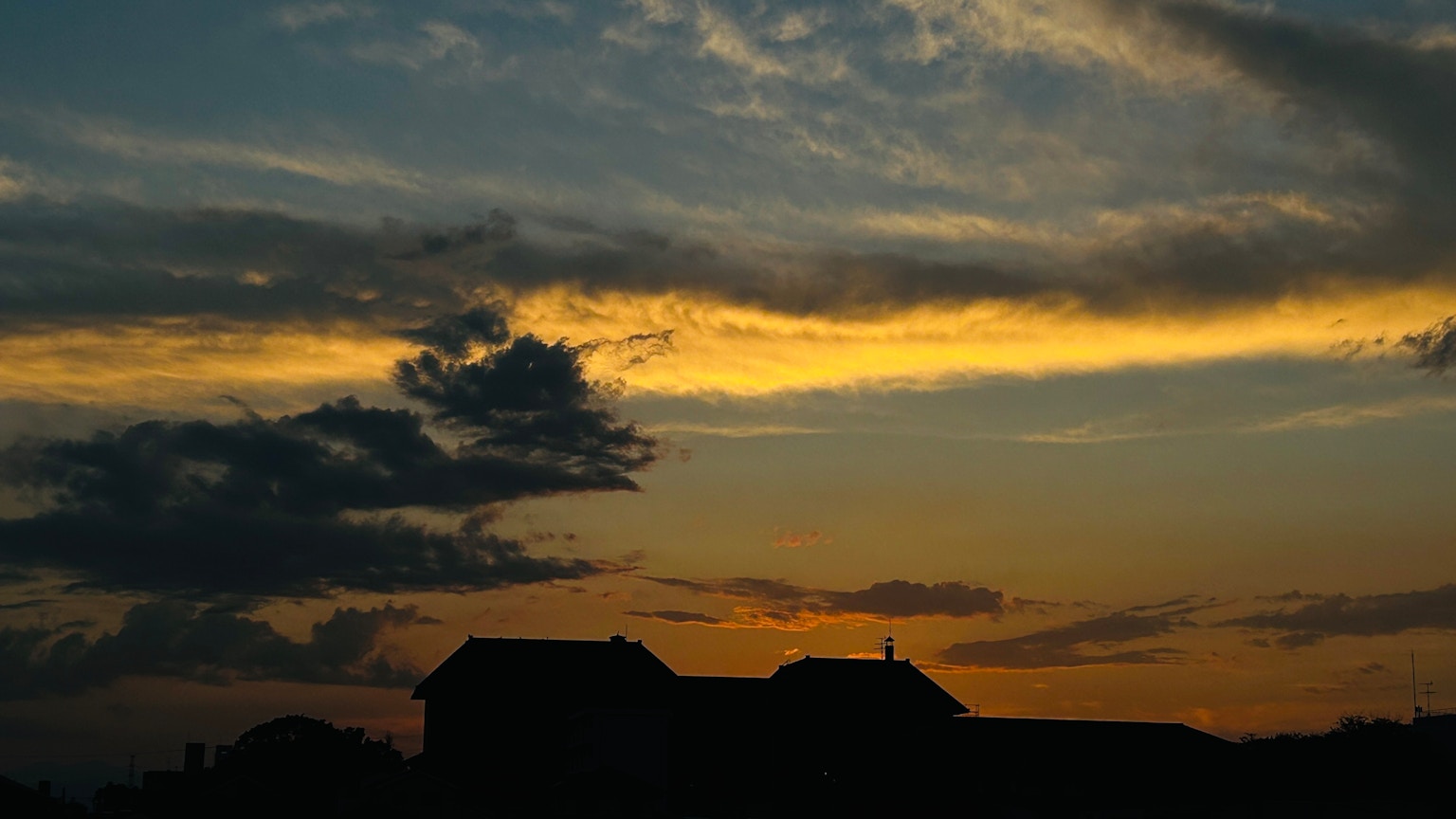 Silhouette of houses against a vibrant sunset sky