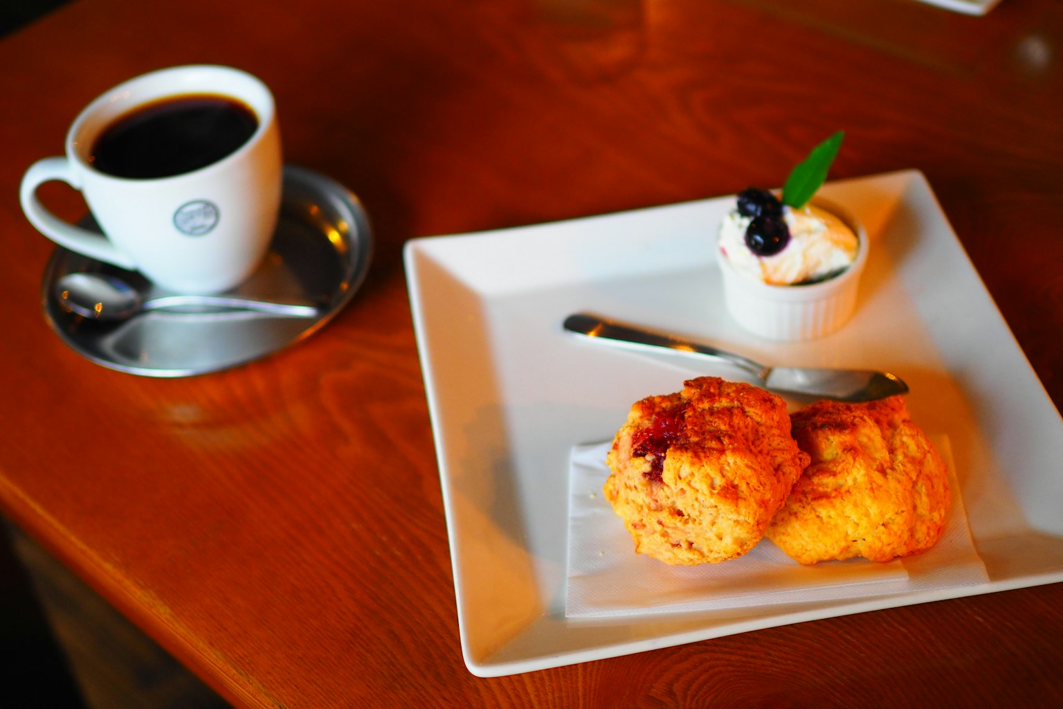 Table de café avec café et scones servis avec de la crème et des myrtilles