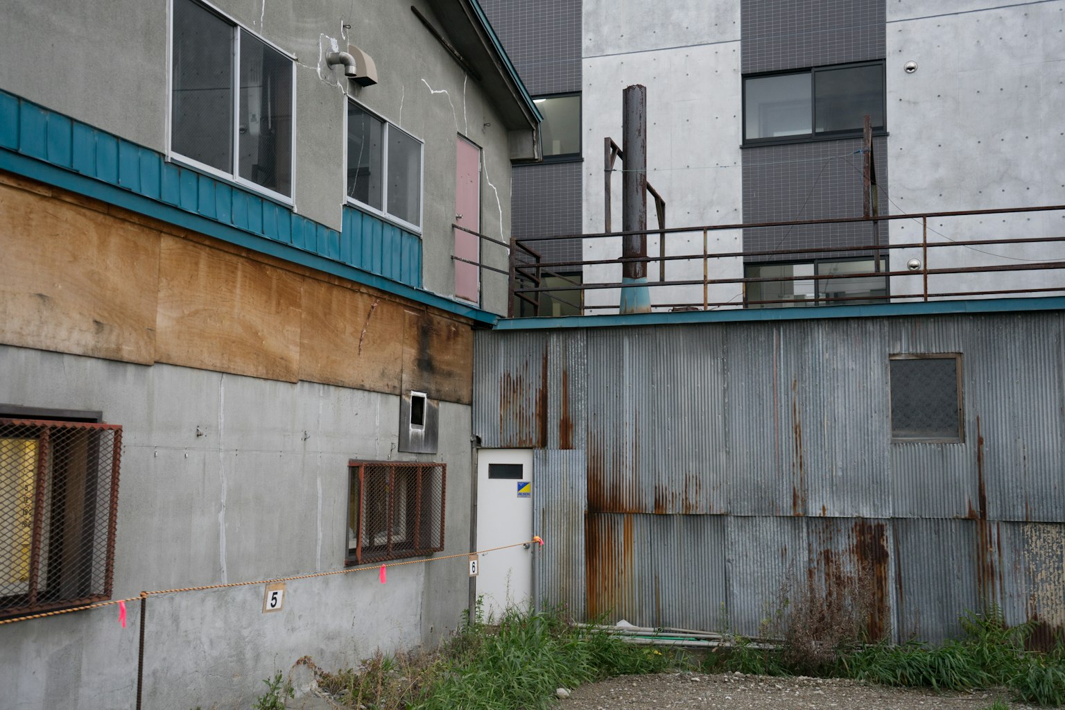 Vista esterna di un edificio invecchiato con un muro metallico