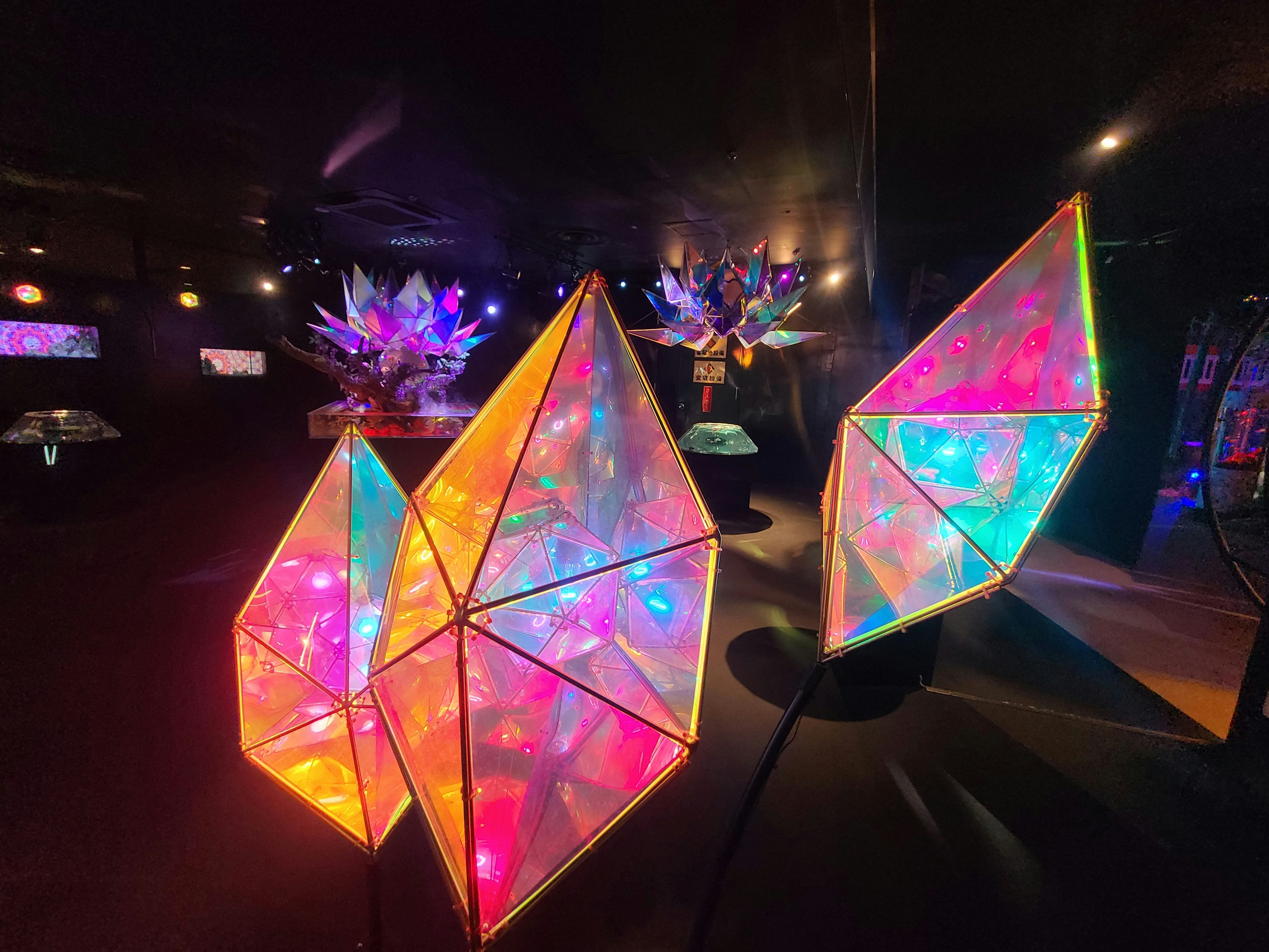 ネオンの光る幾何学アートが並ぶ夜の展示空間