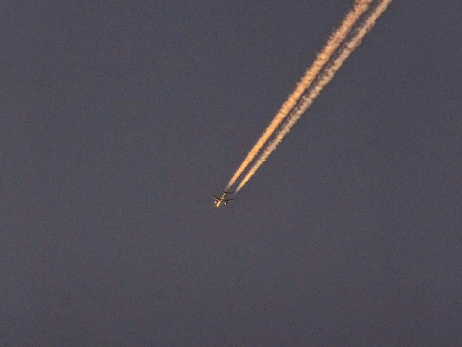 Image d'un avion volant avec une traînée de condensation dans le ciel clair