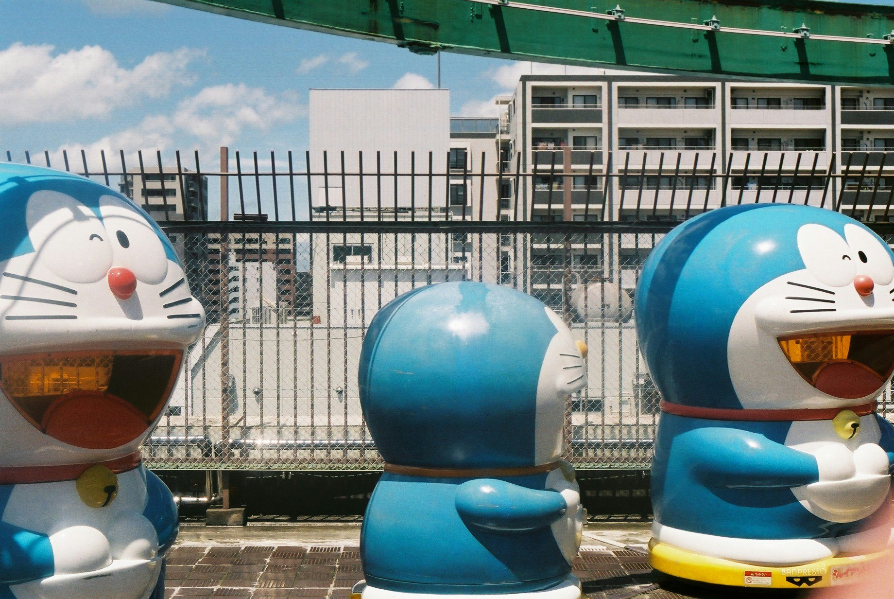 Blue Doraemon character statues lined up outdoors by a fence