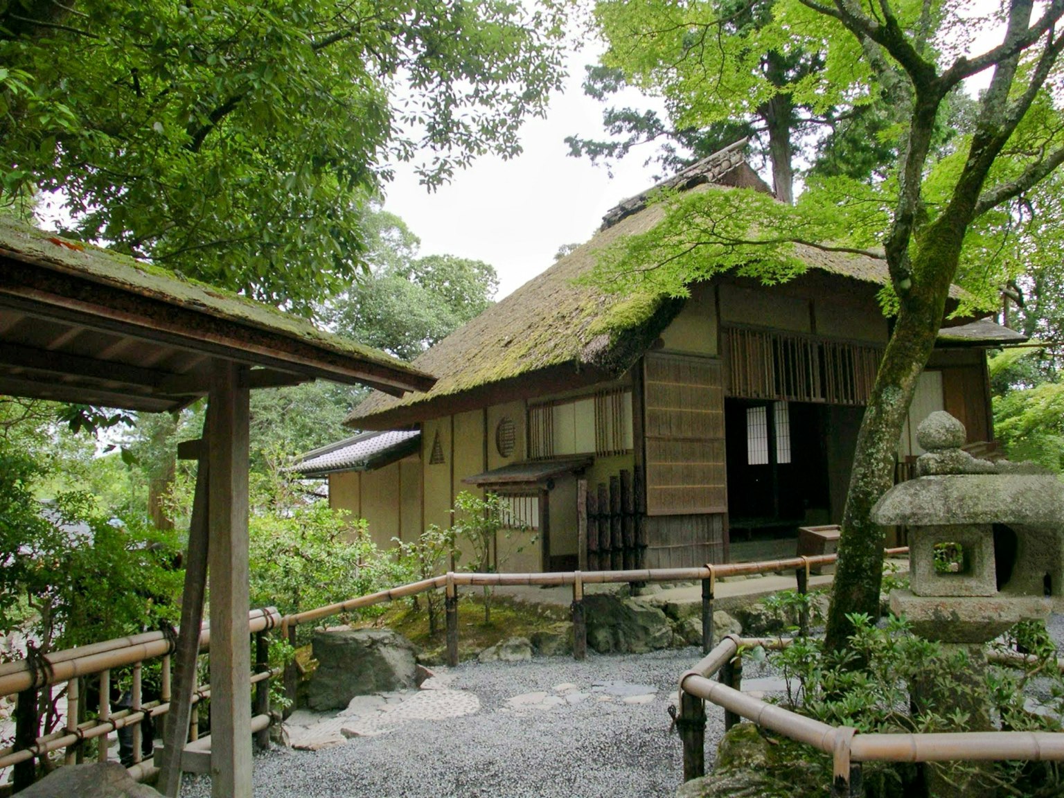 Rumah tradisional Jepang dikelilingi kehijauan dengan lentera batu