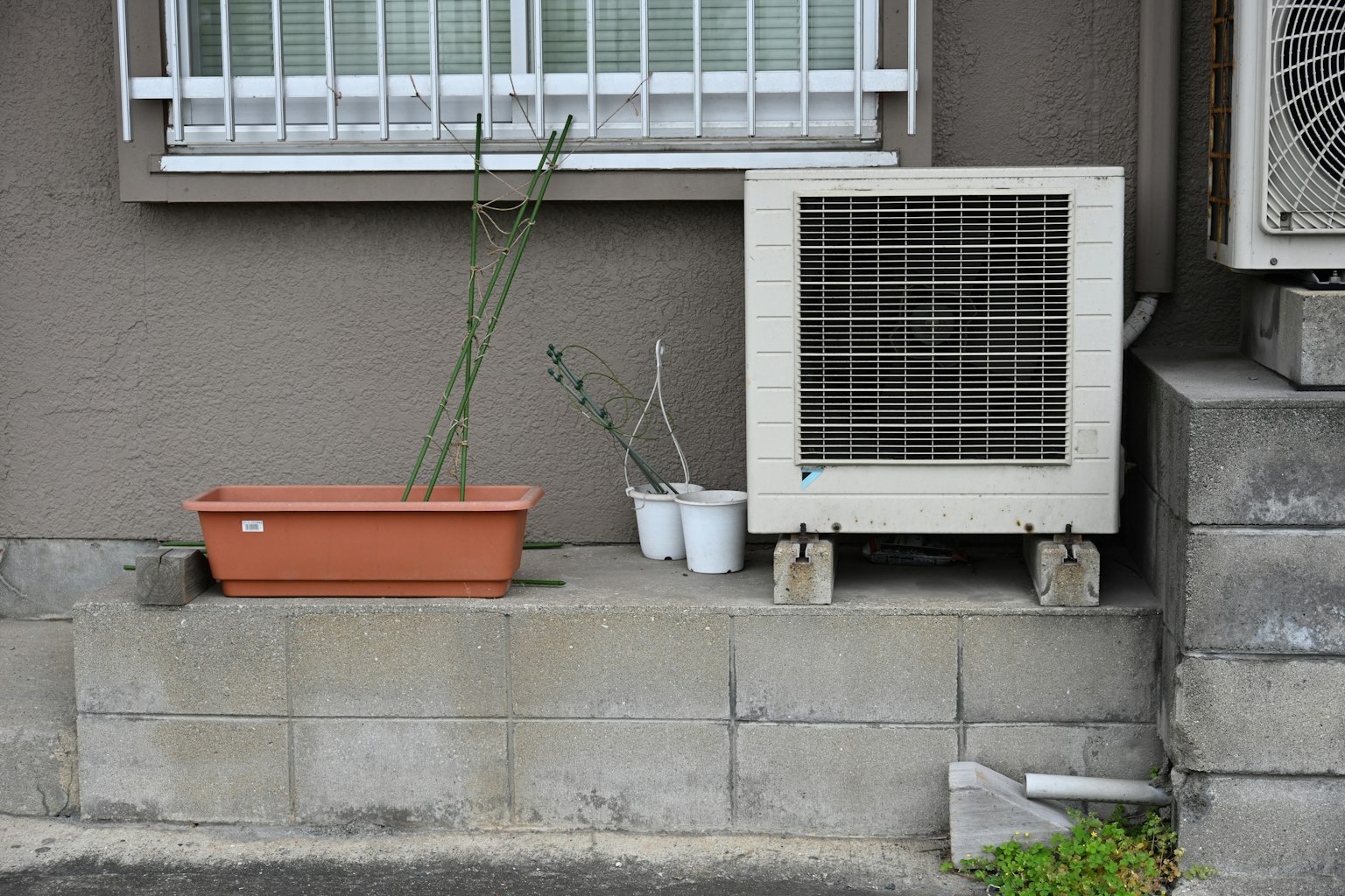 Vista esterna di una casa con un'unità di climatizzazione e un vaso di fiori