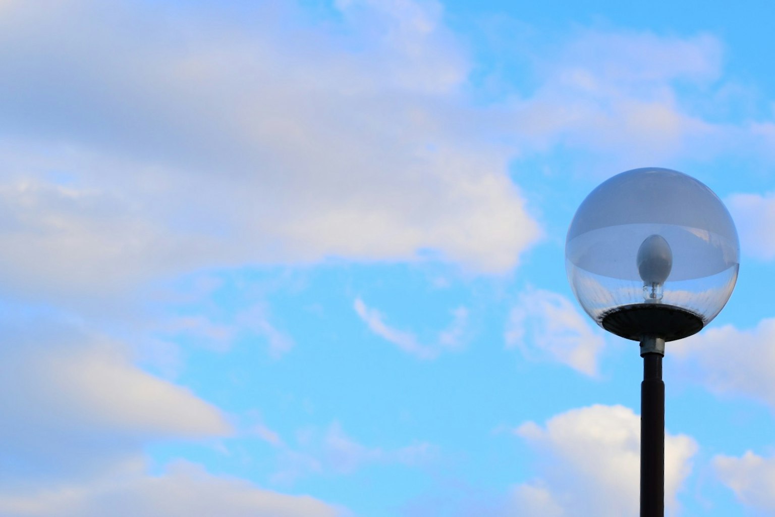 Lampu jalan bulat di bawah langit biru dengan awan
